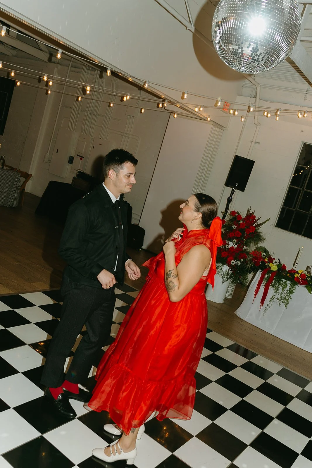 The couple dancing together on the black and white checkered floor at The Revery LA, framed by disco balls and soft reception lighting.