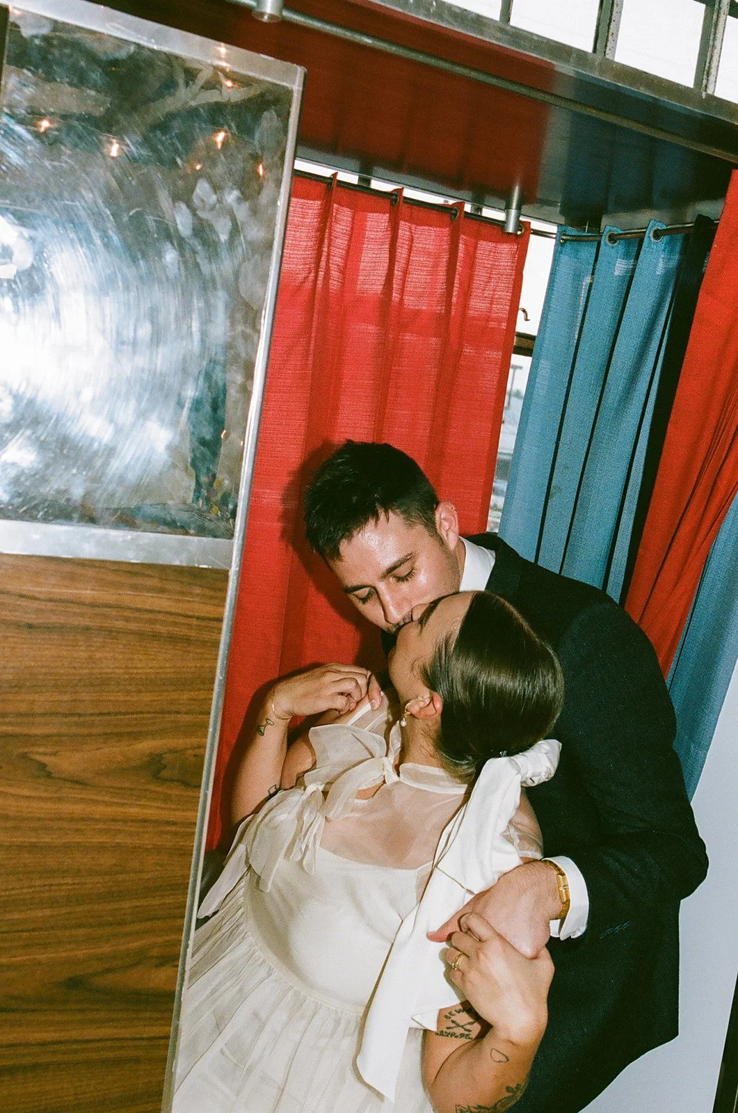 A close, candid moment of the couple kissing in a colorful photo batch at The Revery LA with soft light and vintage textures around them.