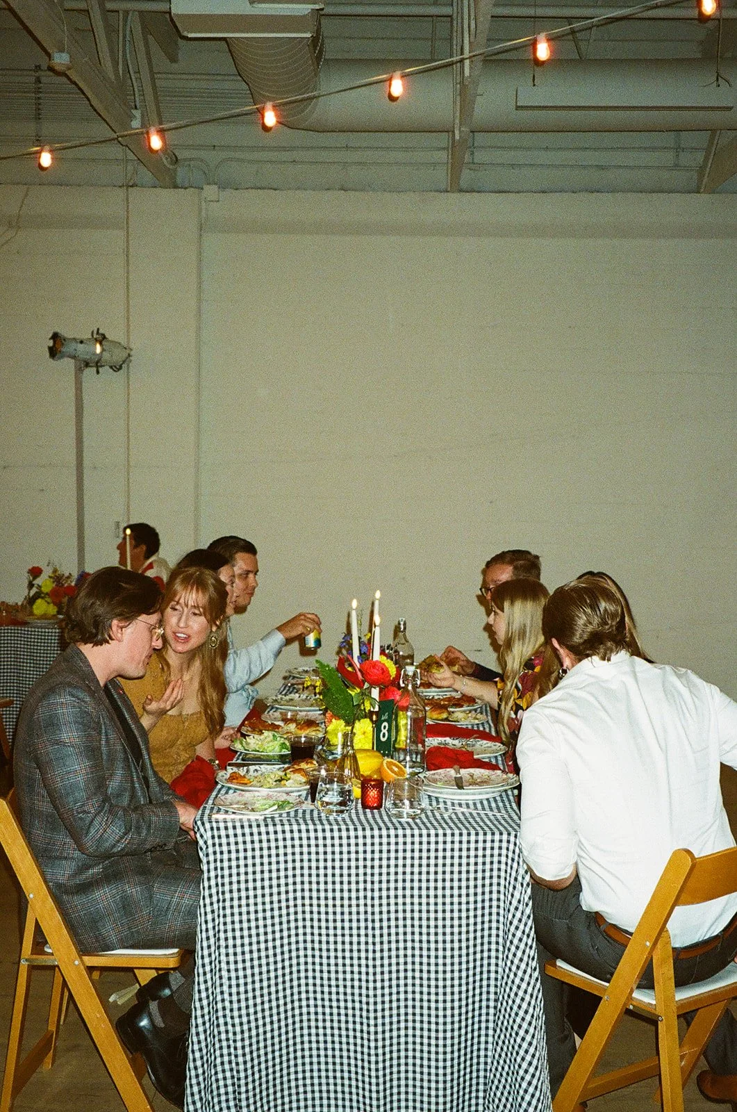 Guests gathered around a long dinner table at The Revery LA, sharing food, drinks, and conversation under warm string lights.