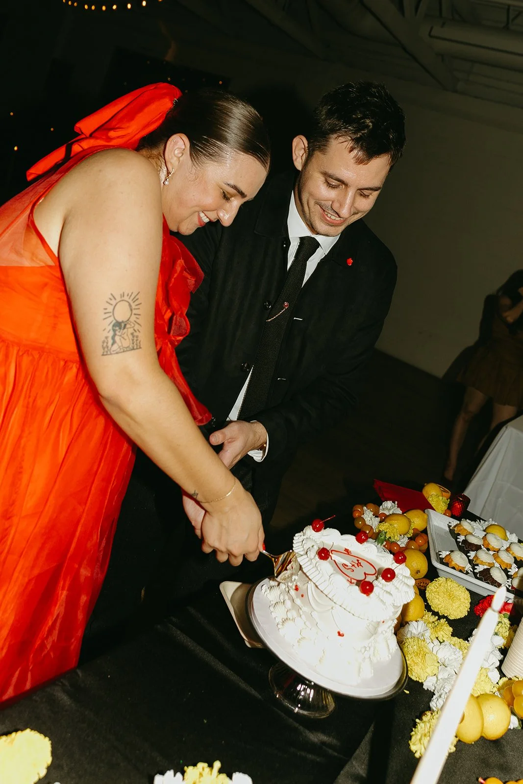 The couple cutting their wedding cake together at The Revery LA, smiling and leaning in during the reception.