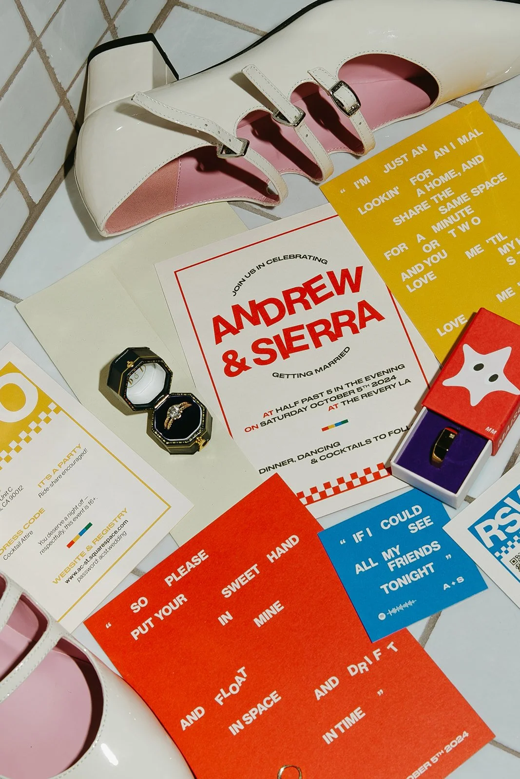 Flat lay of wedding details at The Revery LA including invitations, rings, shoes, and colorful paper goods.