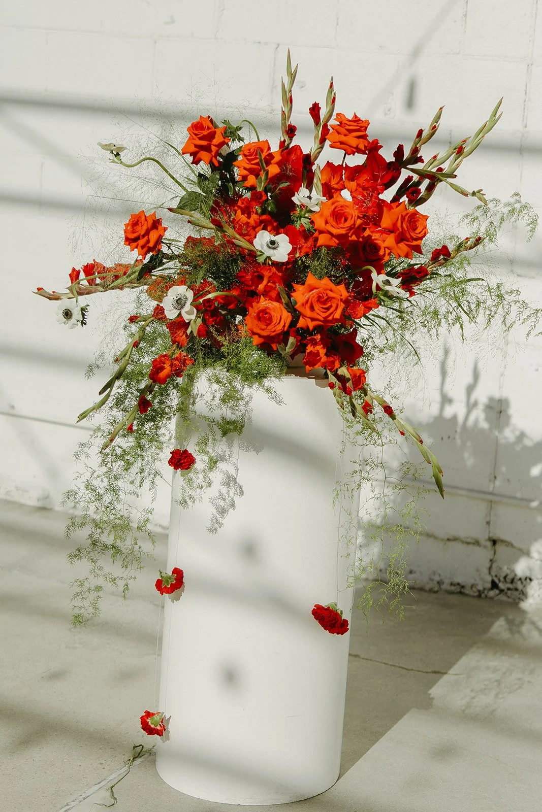 A stunning bright red floral setup for the ceremony spot, planted in a tall white vace and used as the "arch" for the ceremony.