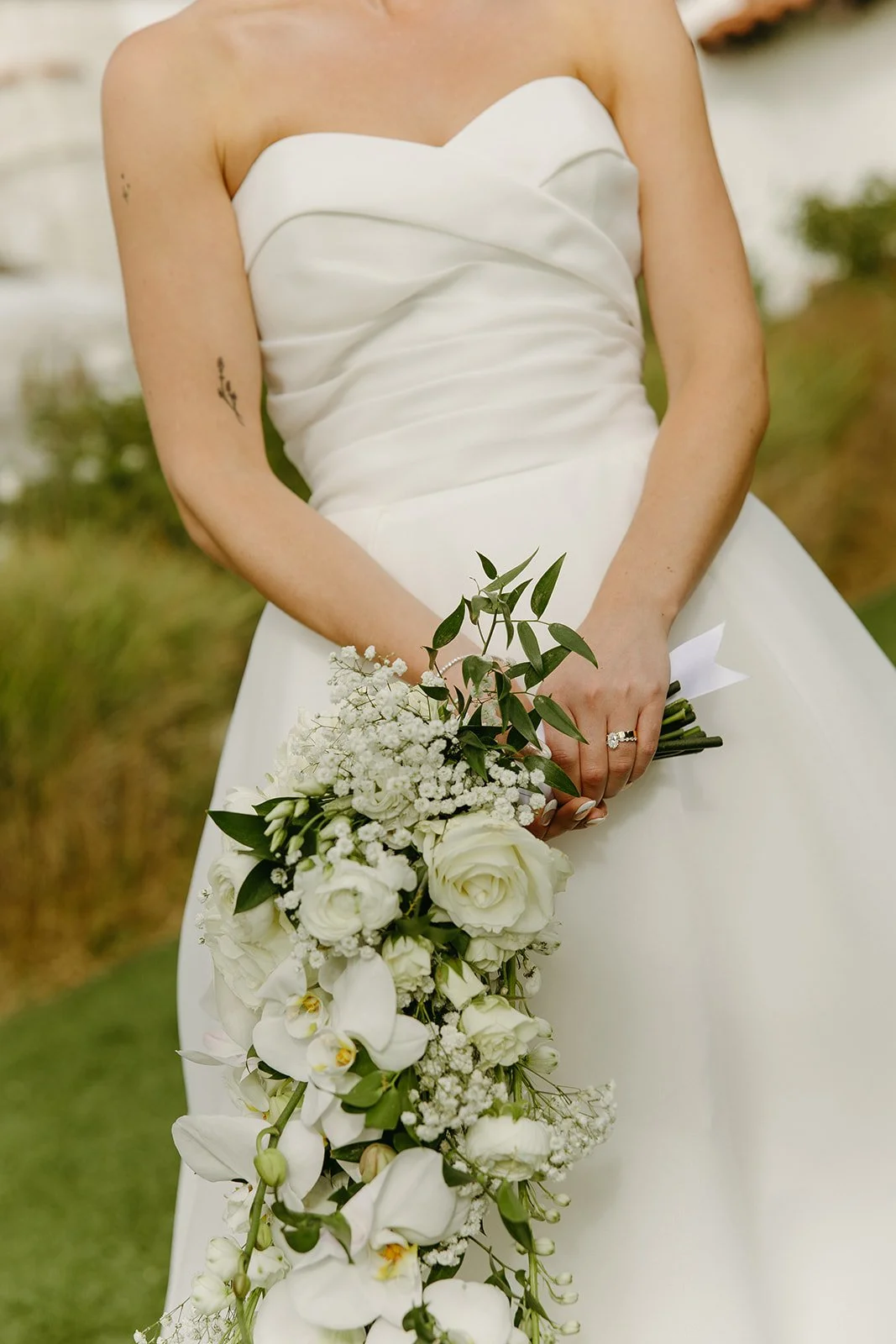 Elegant bride holding a cascading white floral bouquet during portraits at one of the most timeless San Clemente Wedding Venues.