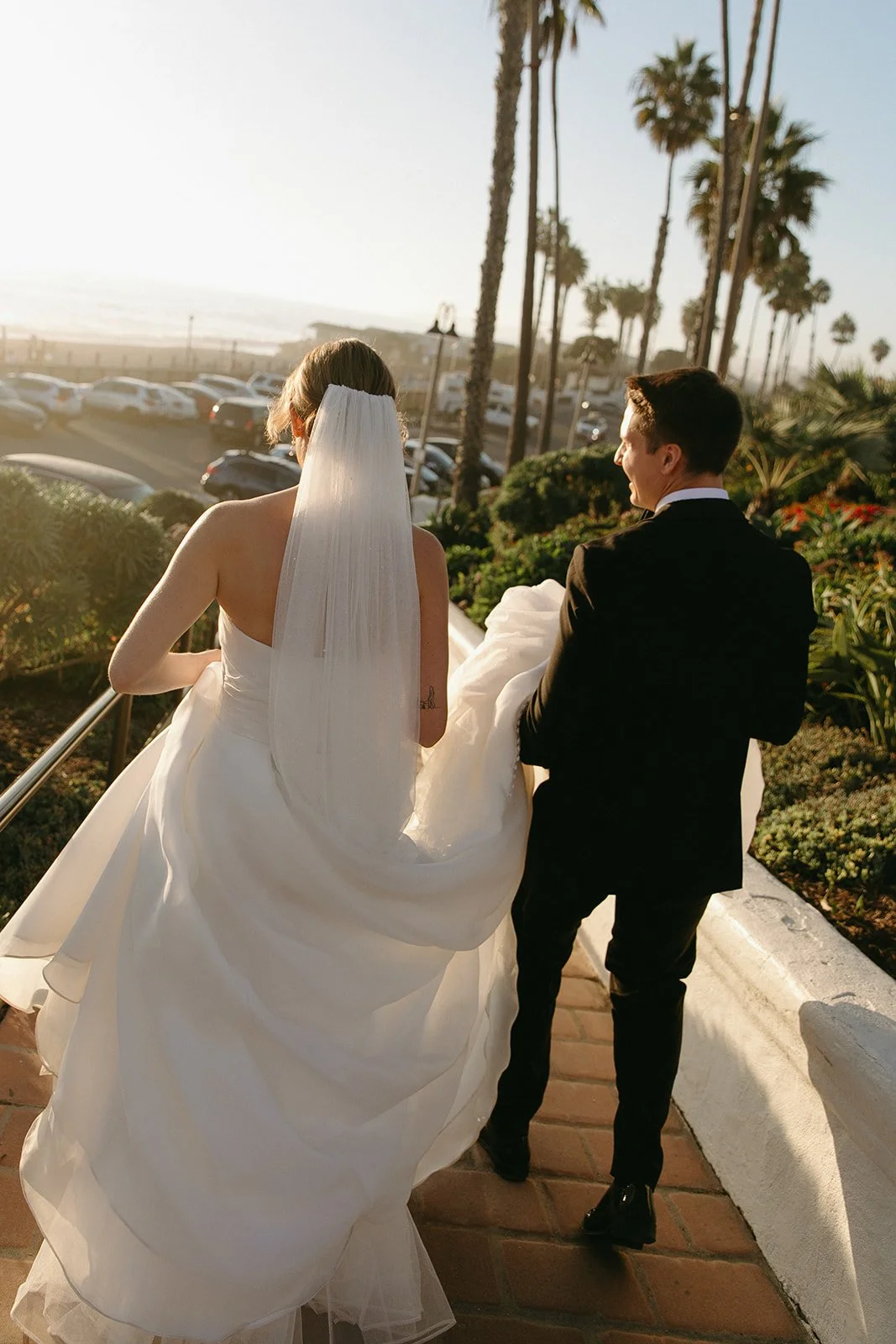 Newlyweds walking along a sunlit path overlooking the ocean, highlighting why San Clemente Wedding Venues are known for coastal views and golden hour portraits.