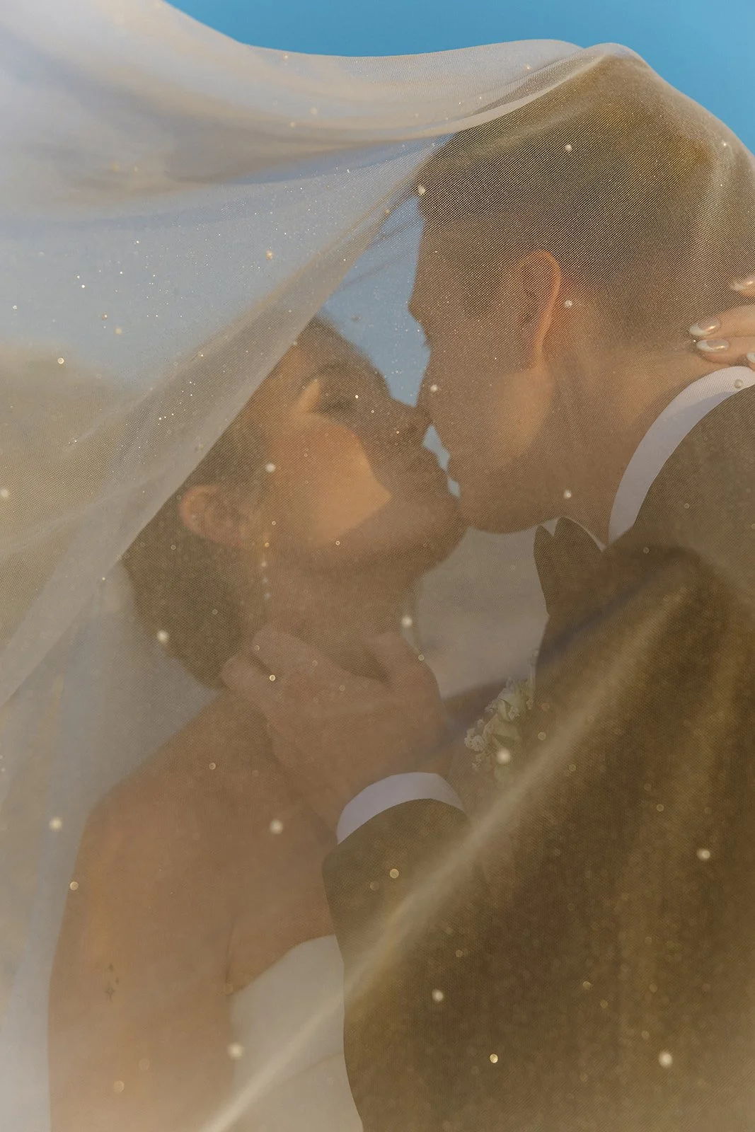 Romantic portrait of the bride and groom kissing beneath the veil during golden hour at one of the most scenic San Clemente Wedding Venues.