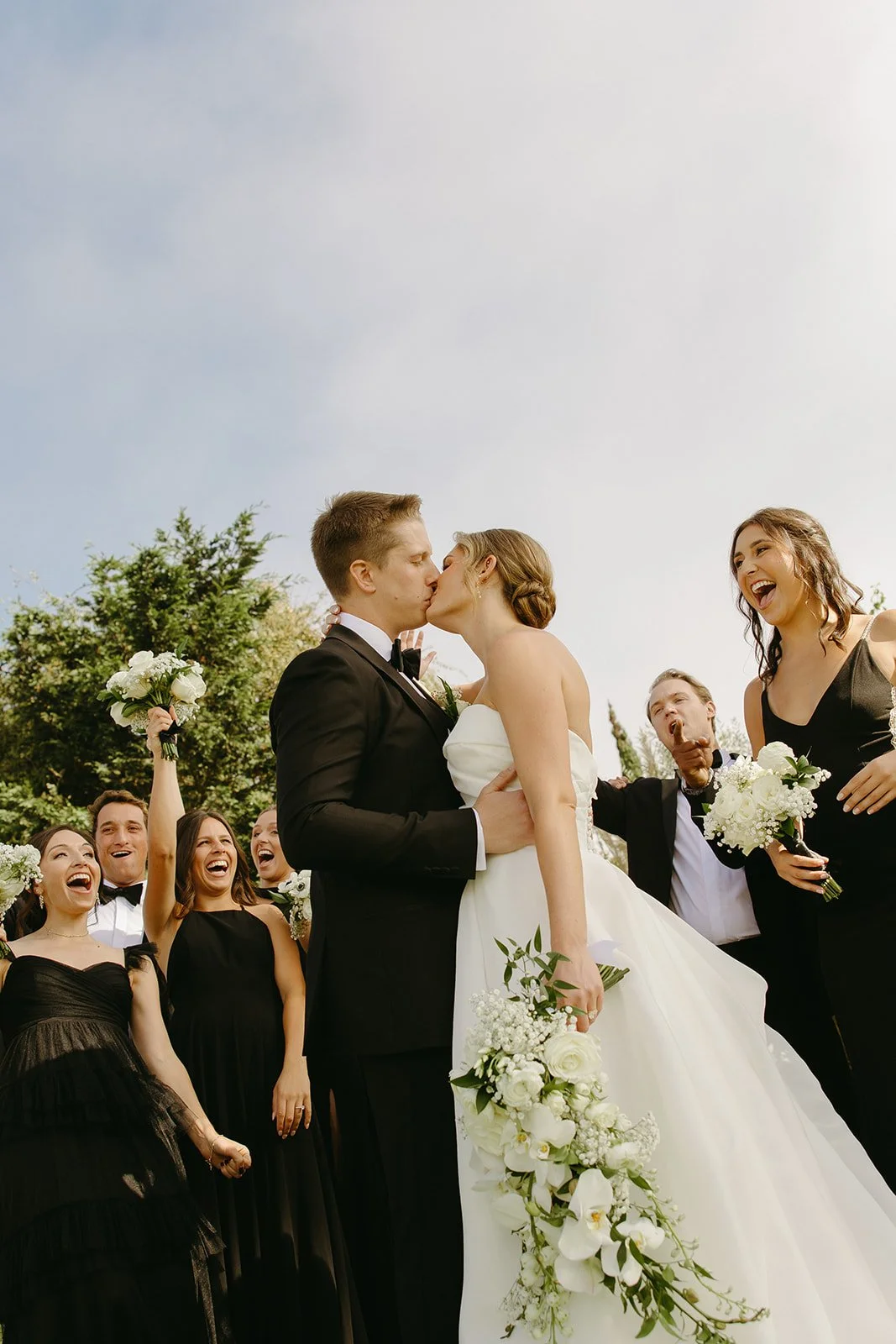 Newlyweds sharing their first kiss surrounded by cheering friends at one of the most timeless San Clemente Wedding Venues.