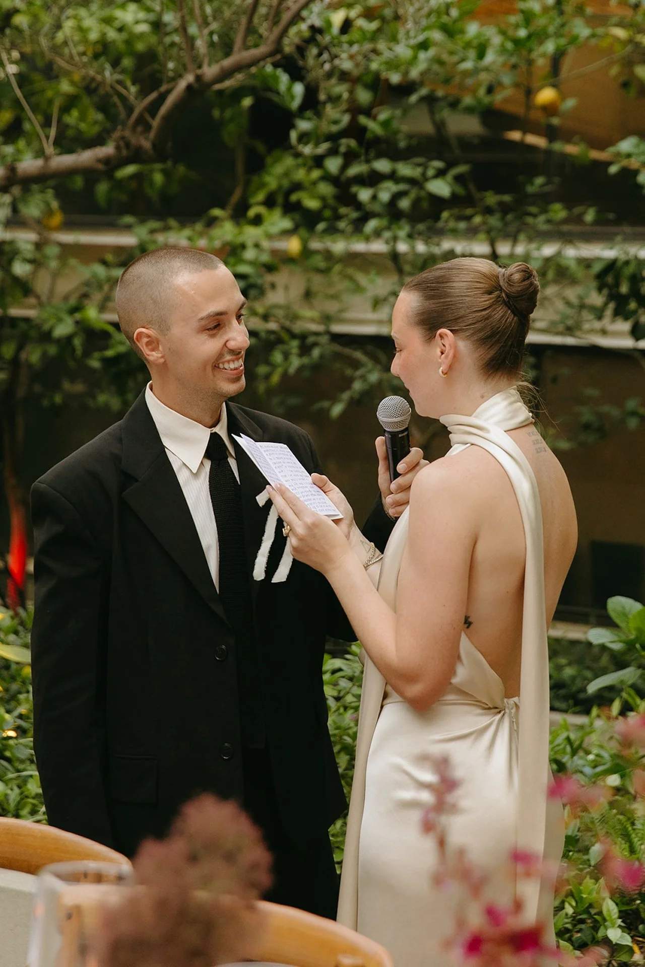 A close-up of the bride reading her vows while smiling at the groom, showcasing Intimate Wedding Ideas for a small, emotional ceremony setting.
