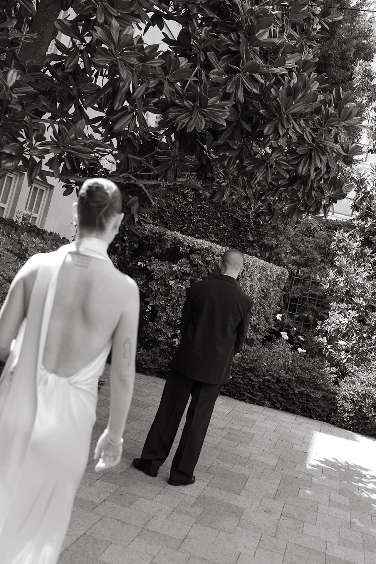 A black-and-white photo of the bride walking toward the groom for a first look in a garden courtyard, capturing Intimate Wedding Ideas with a cinematic, documentary perspective.