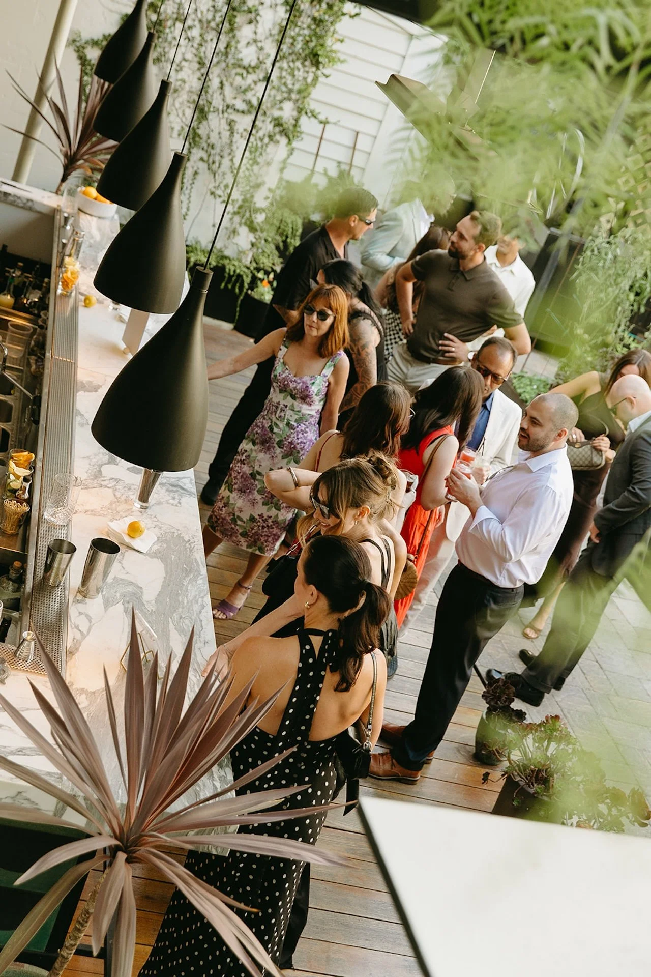 A group of guests dancing together outdoors during the wedding reception, with arms raised and candid movement in a garden courtyard setting.