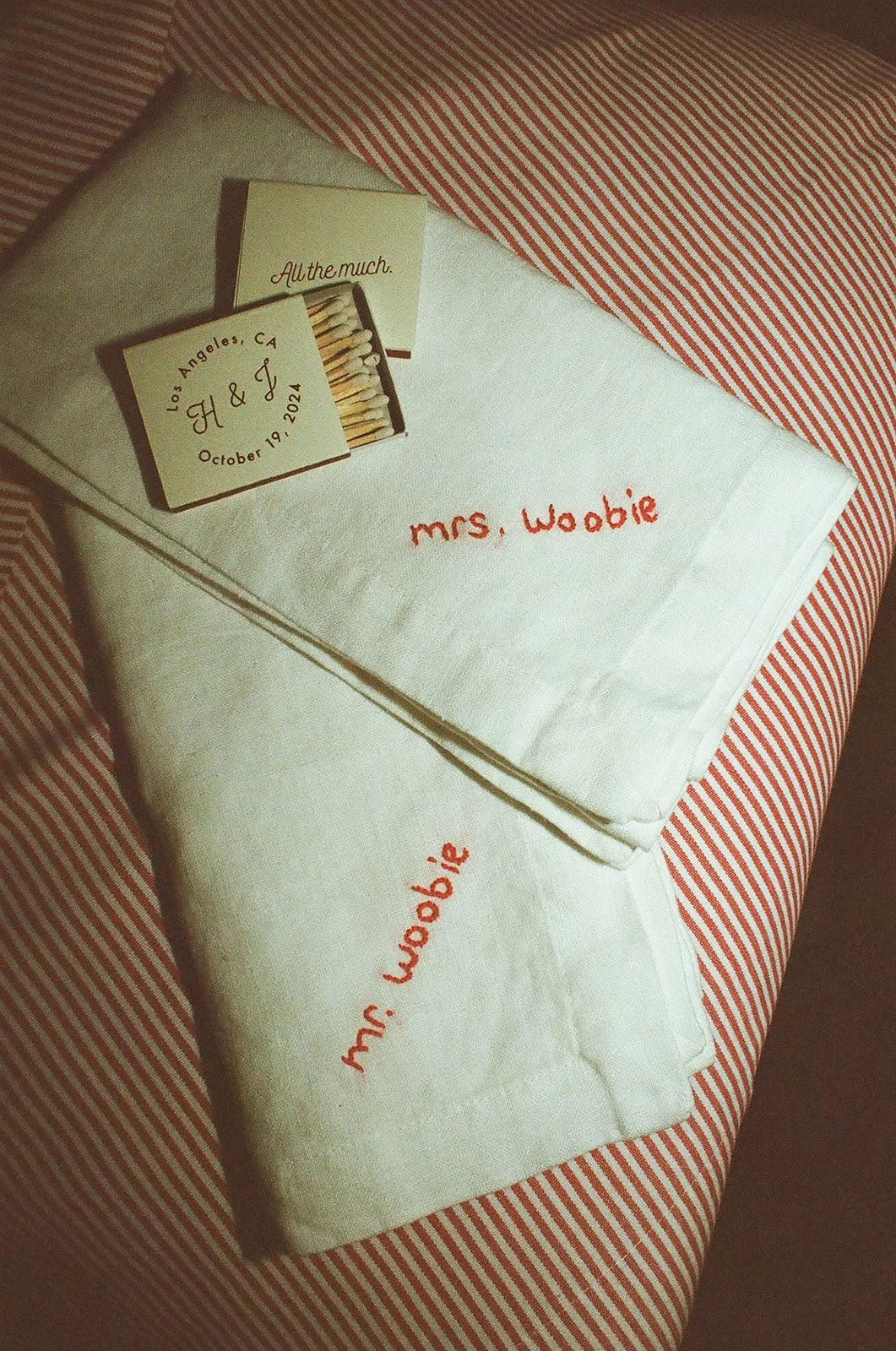 A film photo of hand embroidered napkins and match stick boxes with the couples name on it.