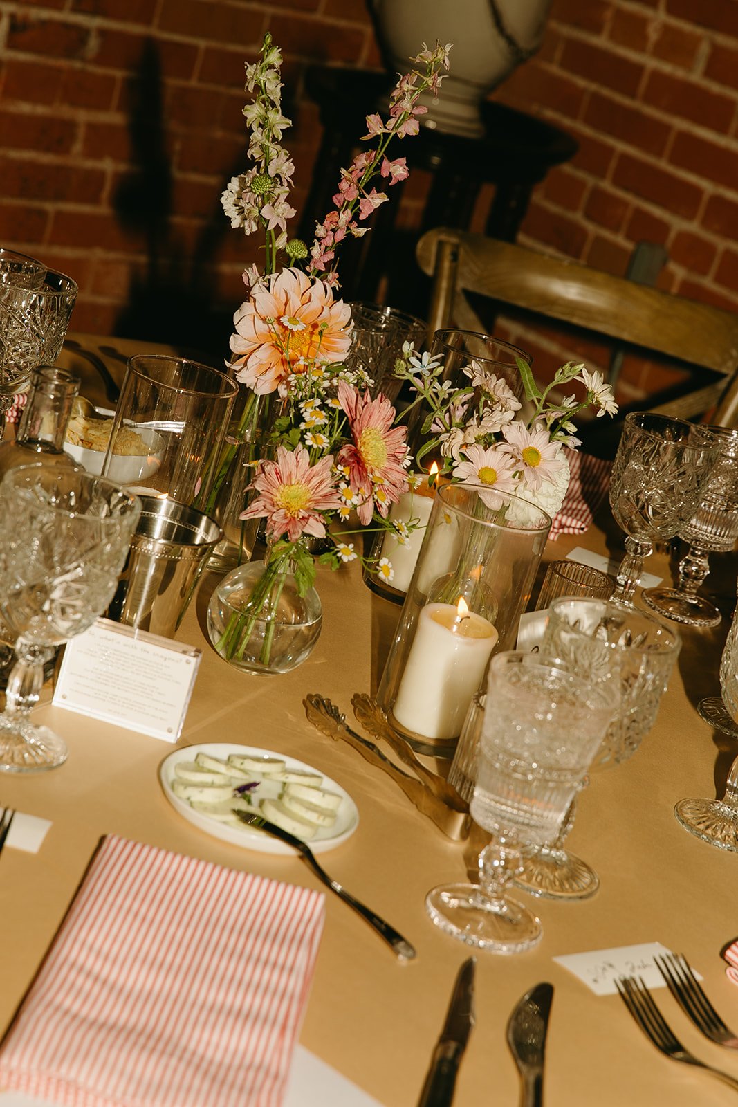 A detail shot of the wedding table setup with pink florals, candles, vintage glasses, and more.