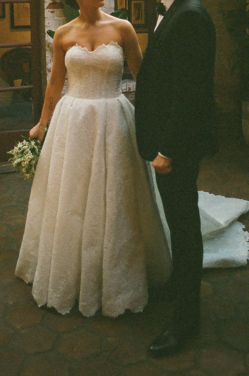 A romantic film photo from the chin down of the bride and groom walking hand in hand at a DTLA wedding venue for their bride and groom portraits.