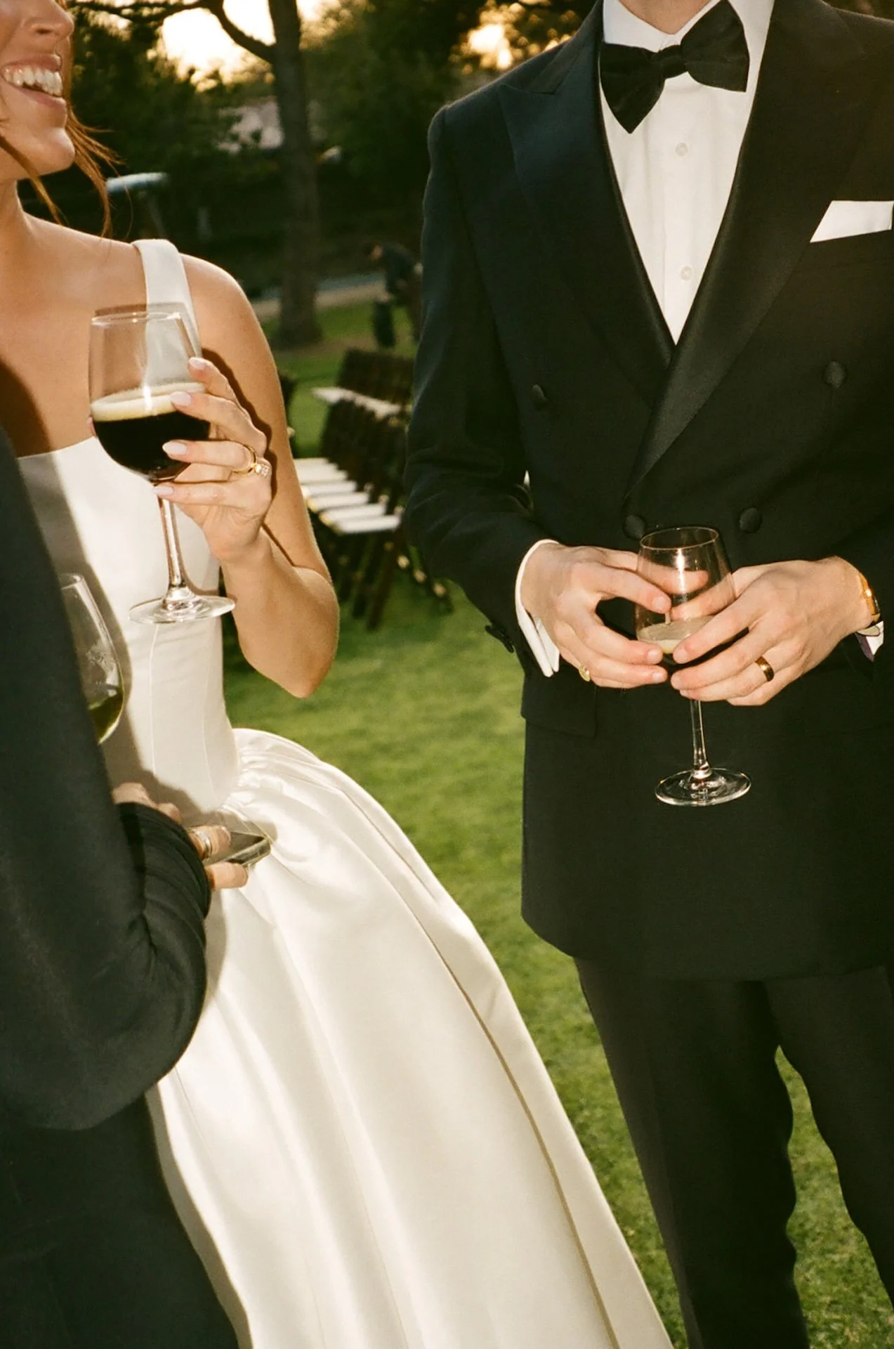 Bride and groom toasting drinks during cocktail hour in formal black tie attire at The Ranch at Laguna Beach wedding reception.