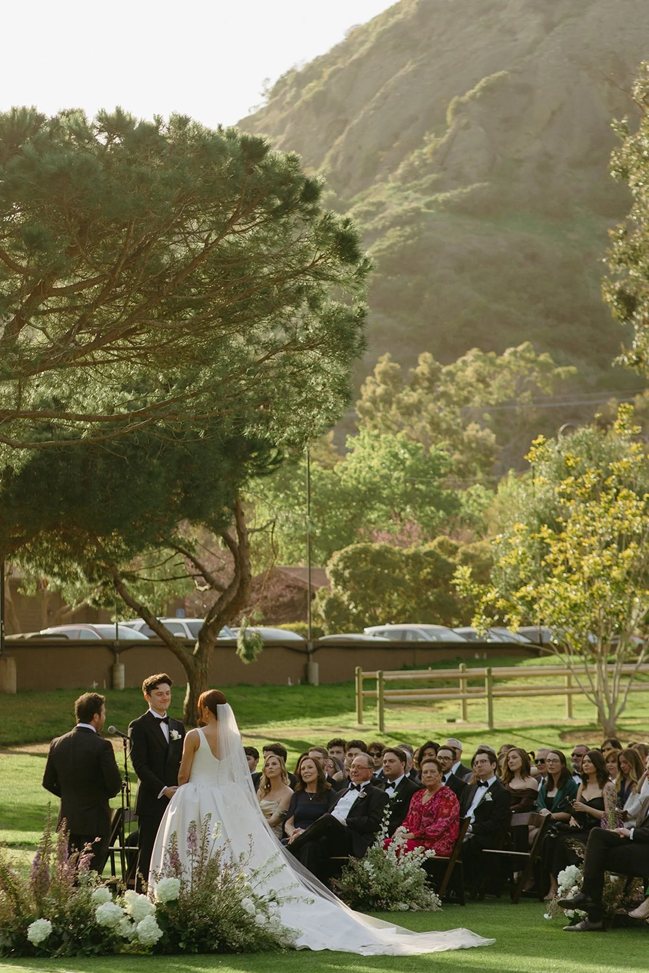 Outdoor wedding ceremony with guests seated on the lawn surrounded by florals and scenic Laguna Beach canyon views.
