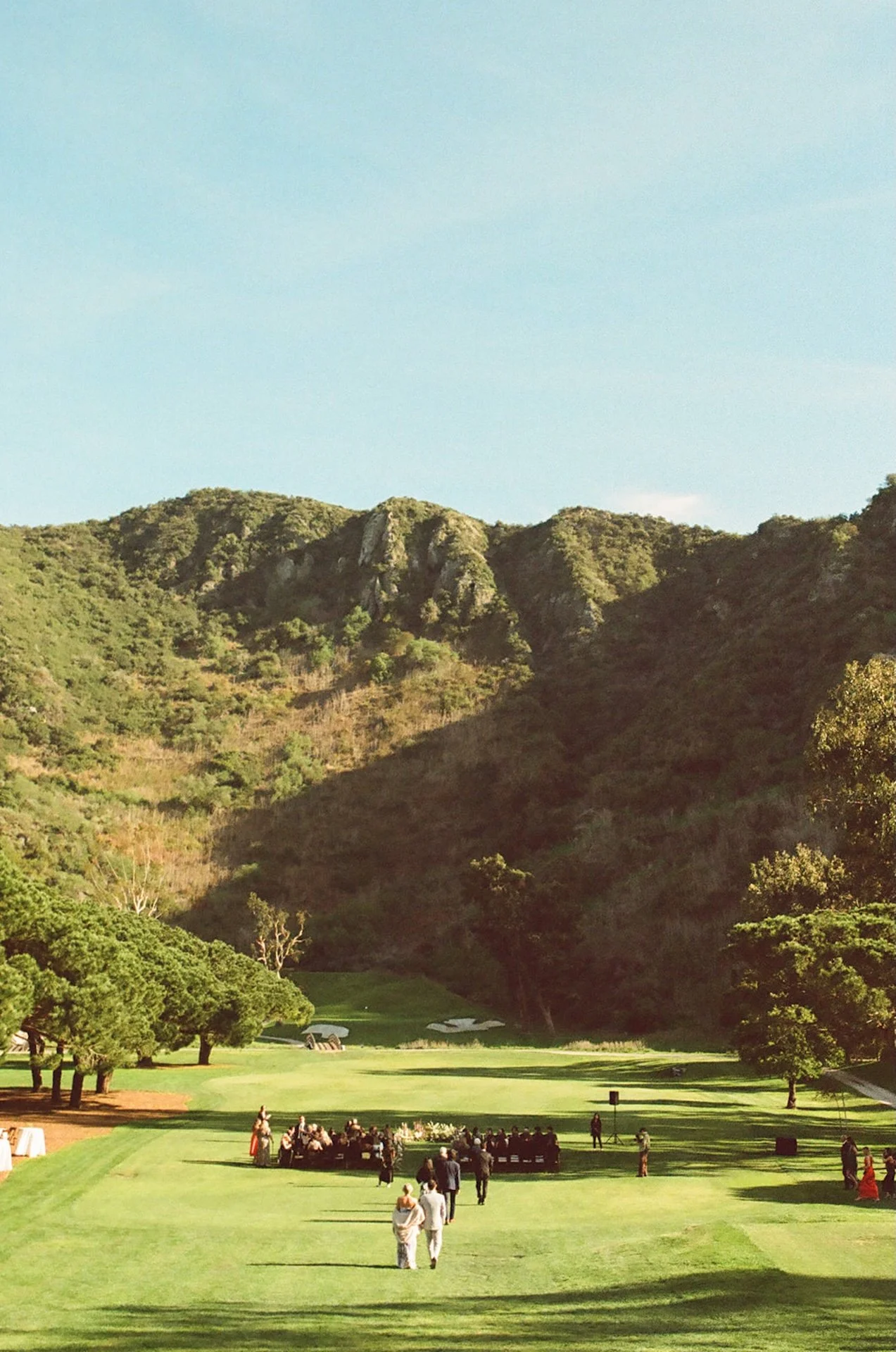 Wide landscape view of the ceremony setup on the golf course surrounded by mountains at The Ranch at Laguna Beach wedding venue.