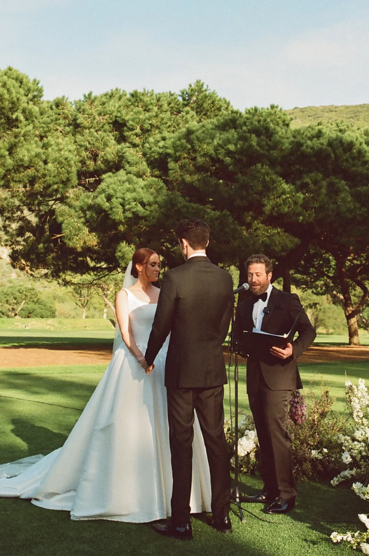 Bride and groom exchanging vows during their outdoor ceremony with lush florals at The Ranch at Laguna Beach wedding.