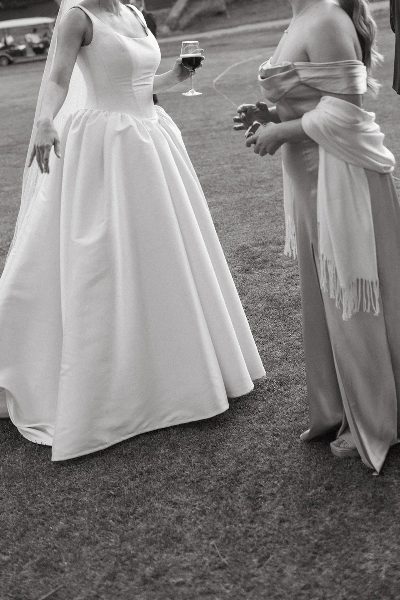 Bride laughing while holding a glass of red wine during cocktail hour on the lawn at The Ranch at Laguna Beach wedding.