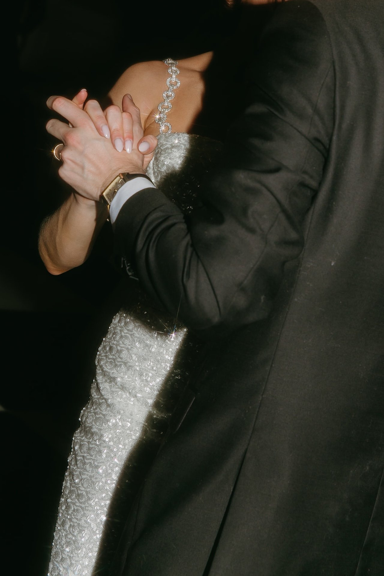 Close up of bride and groom holding hands while dancing during their evening reception celebration.