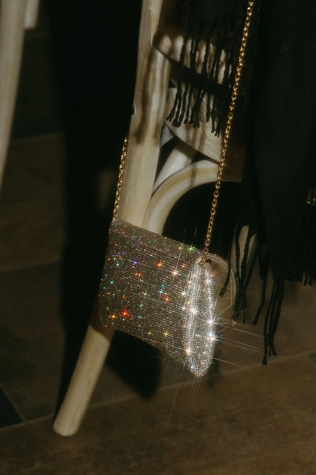 A sparkling detail shot of the brides bedazzed crossbody purse hanging on a chair during the reception.