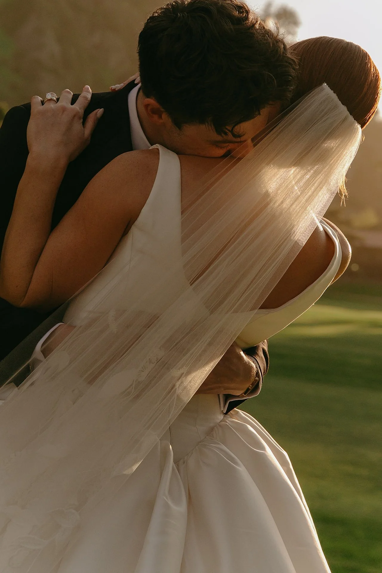 Close up of bride and groom embracing during golden hour portraits with soft sunset light.