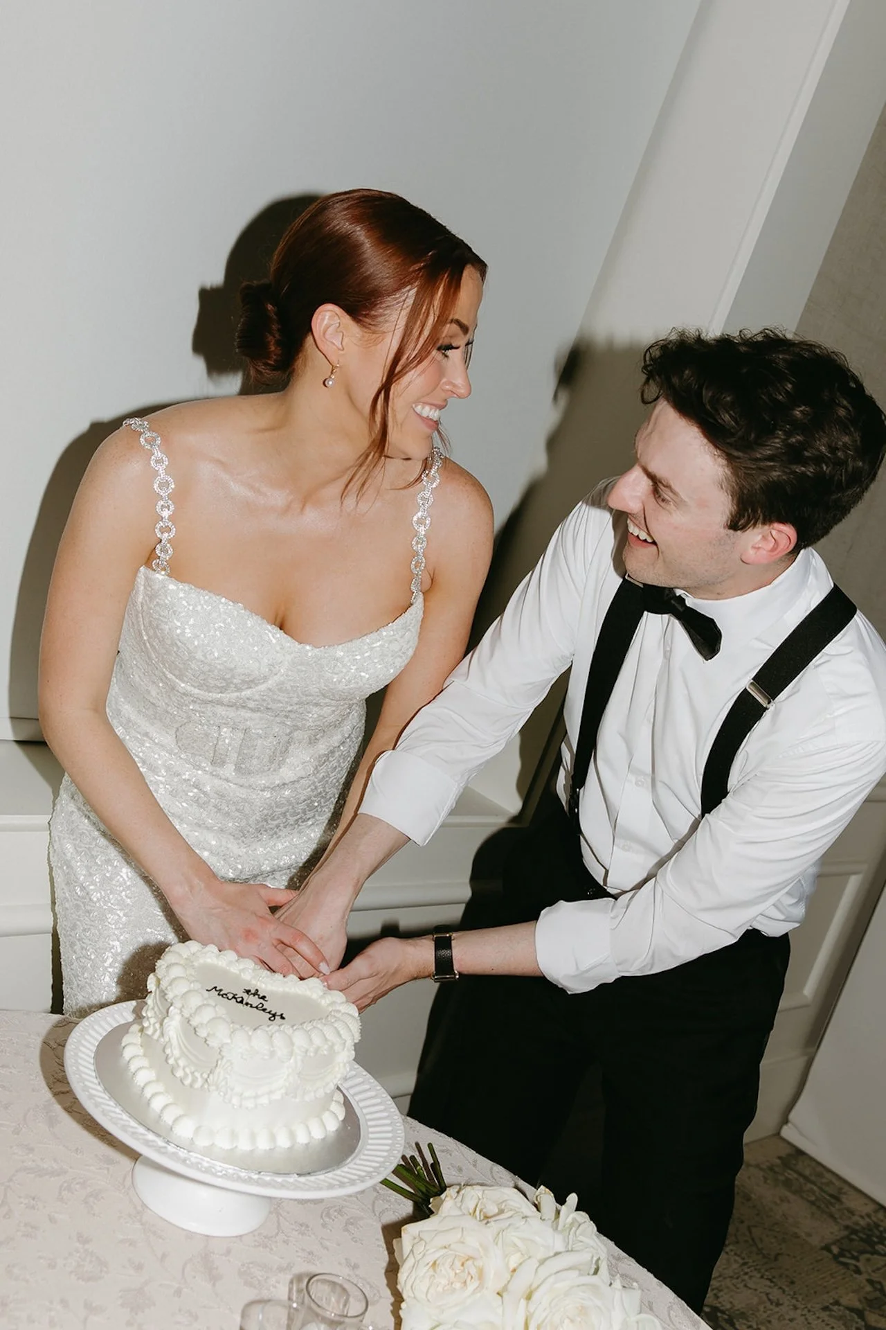 A elegant flash photo of the bride and groom cutting into their cake.