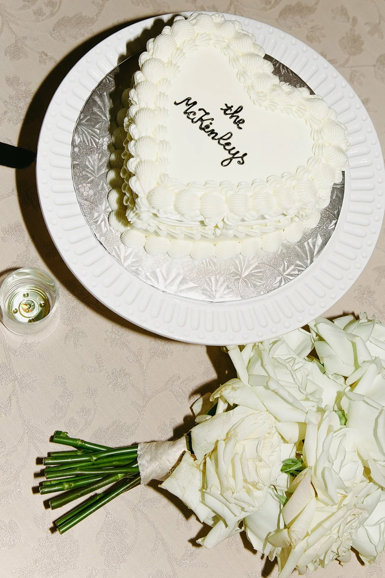 A flash photo of an elegant white cake that has "The McKinley's" written on it in black.