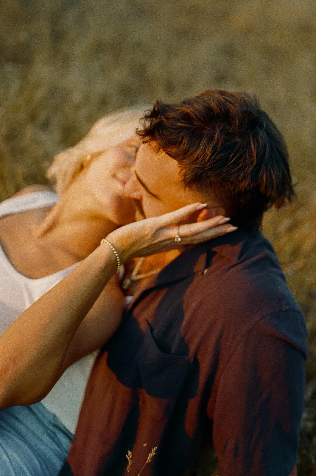 Close up of the bride leaning her head onto her partner while holding his face, engagement ring visible.