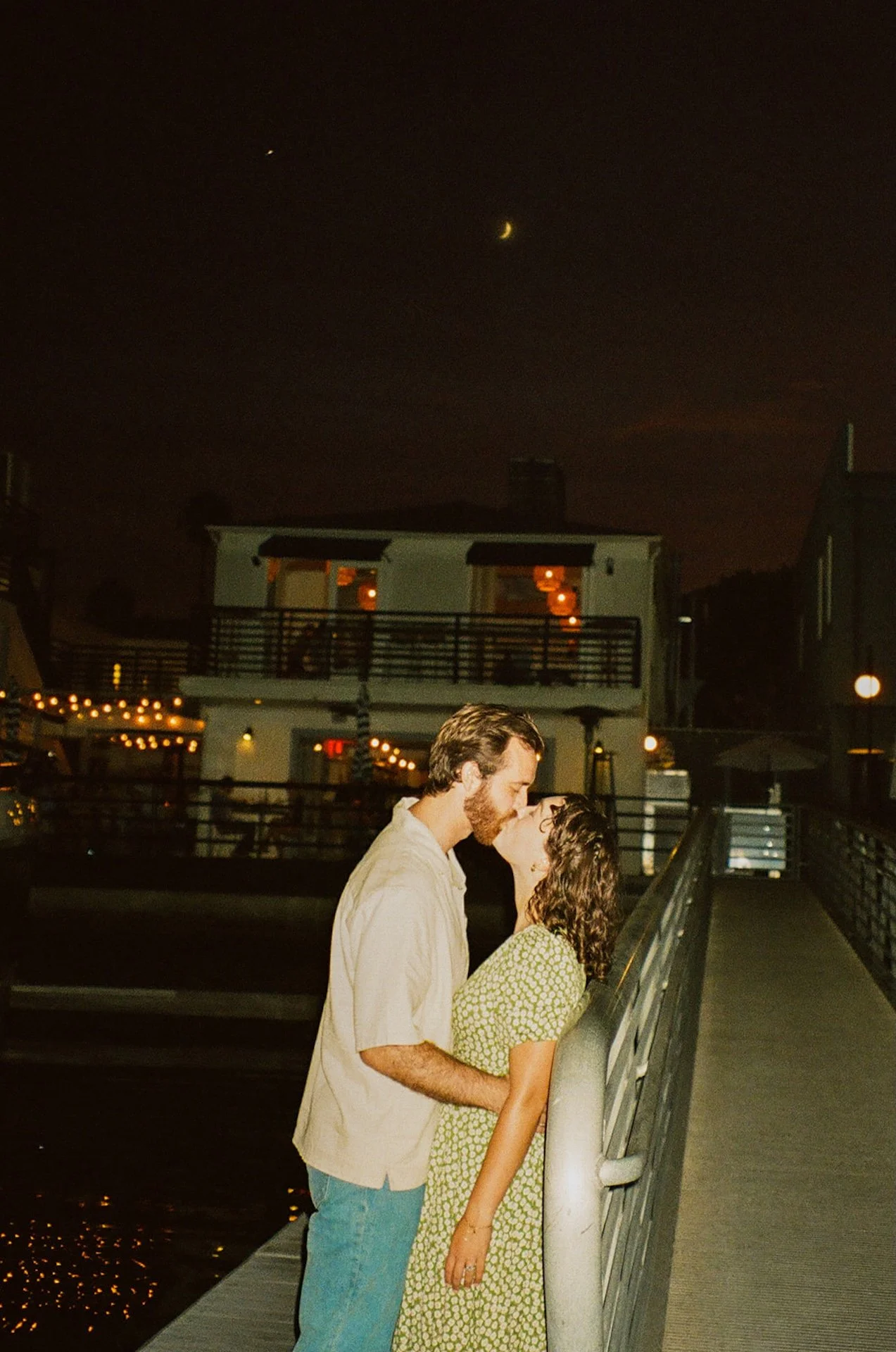 A candid flash photo of a couple kissing on the docks during their romantic newport beach engagement photos.