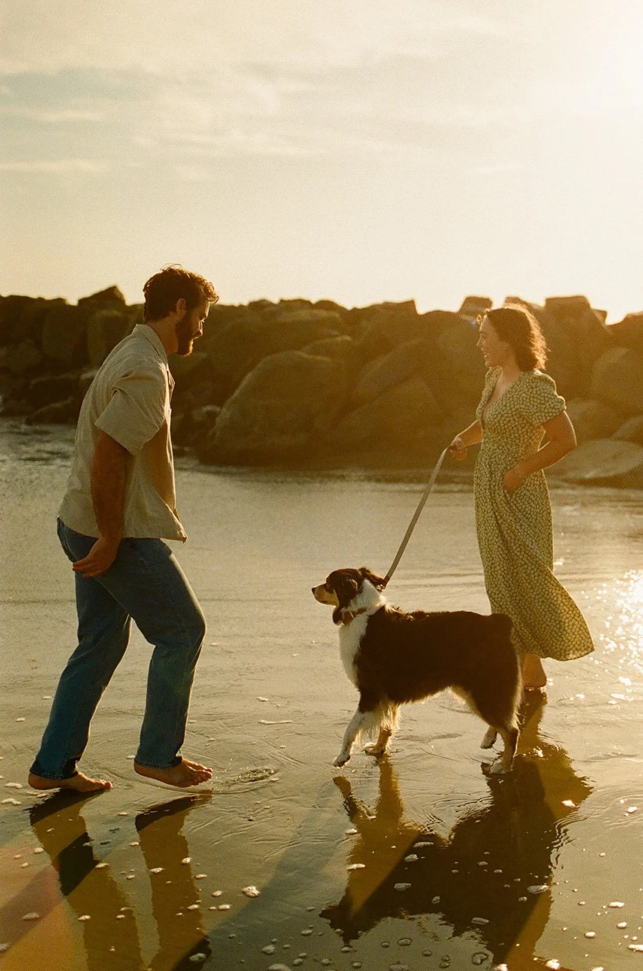 A couple playing on the beach with their dog for a candid photo during their newport beach engagement photos.