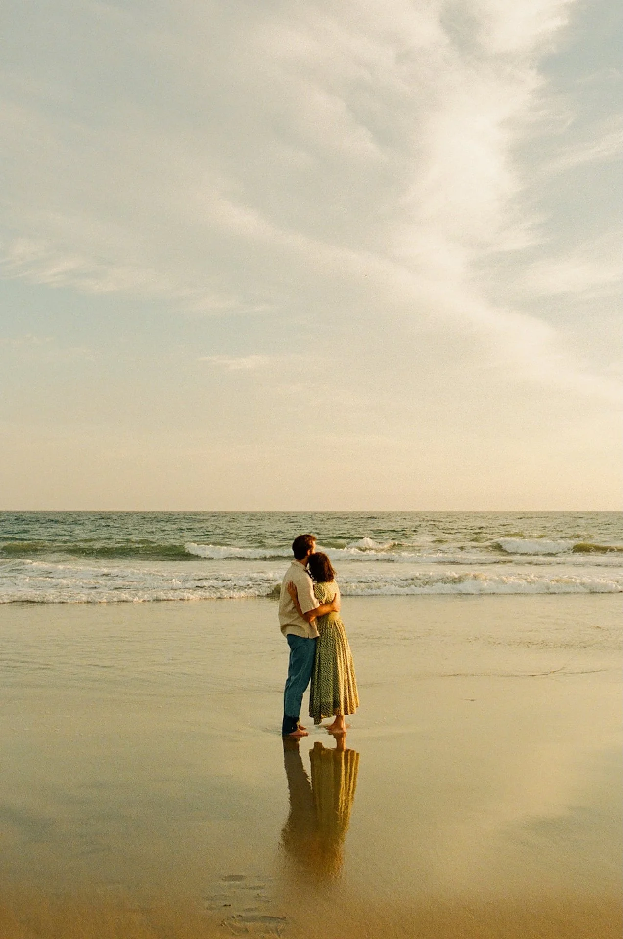A wide shot of an engagement couple hugging and looking out at the ocean during their newport beach engagement photos.