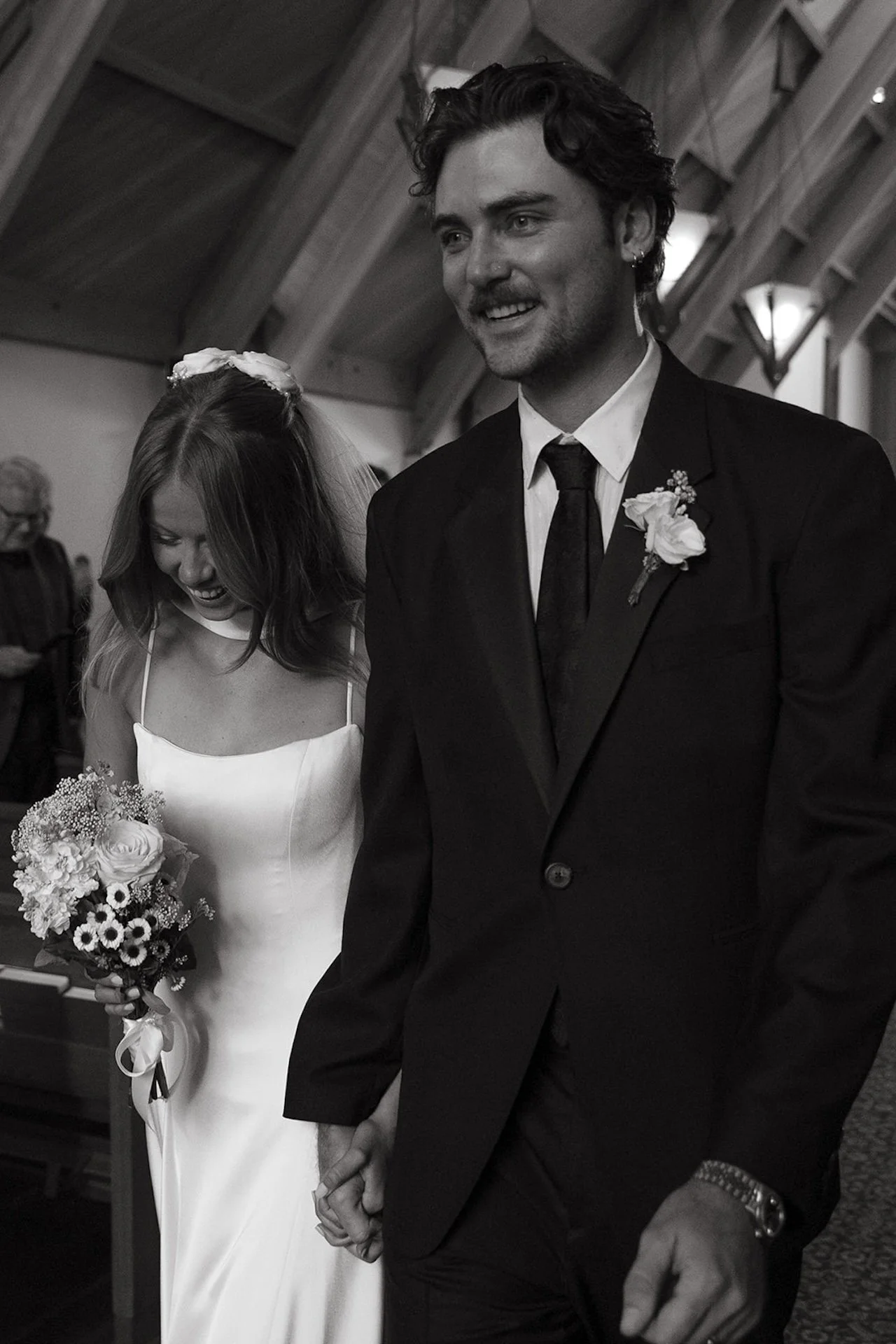 Newly married couple walking down the aisle smiling and holding hands during their Laguna Beach wedding celebration.