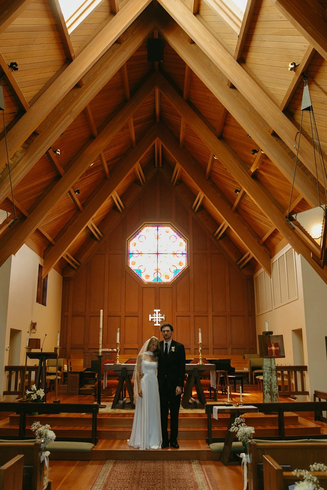 Bride and groom standing together at the altar inside a warm wood chapel during their intimate wedding ceremony.
