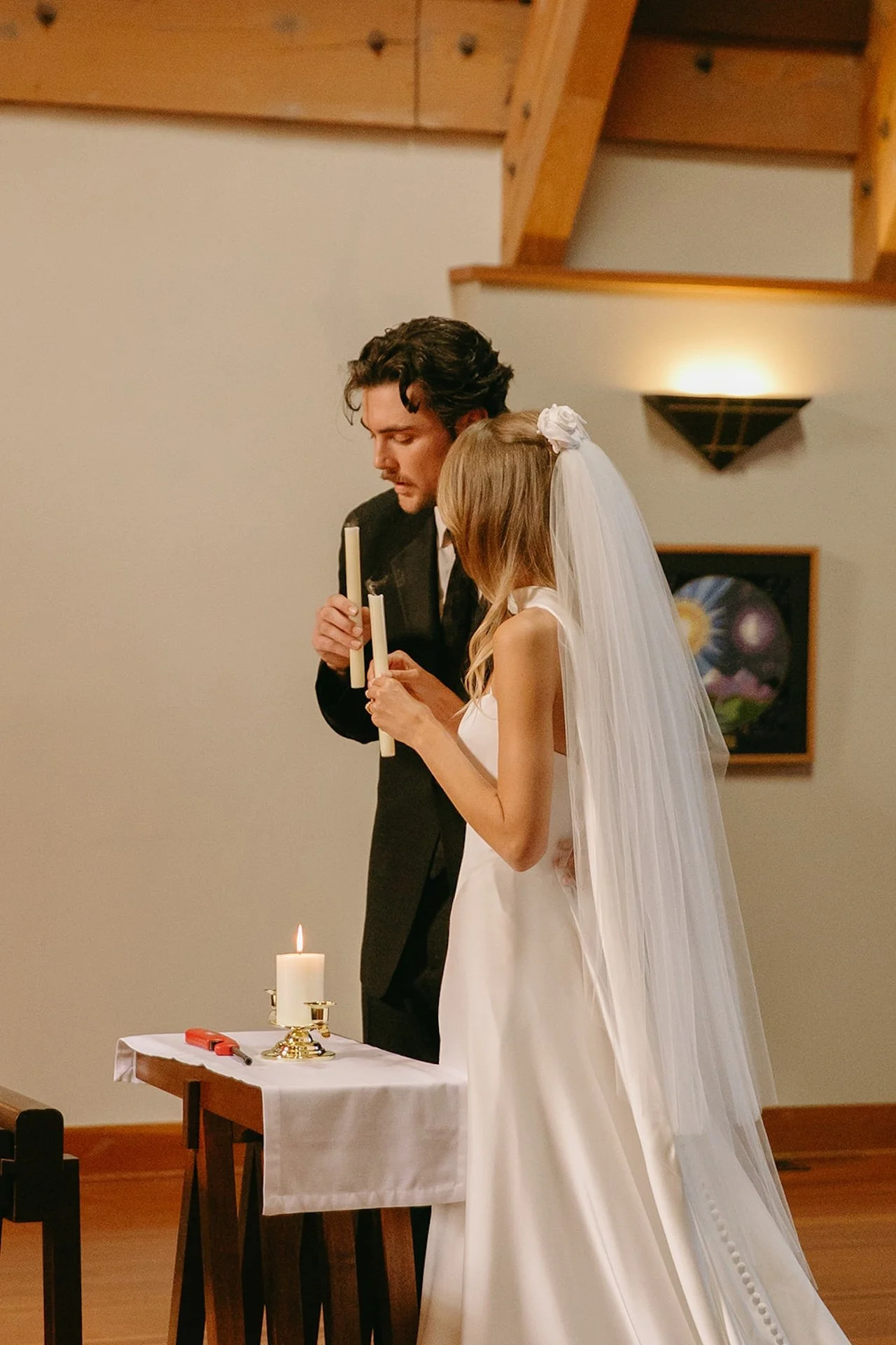 Bride and groom lighting unity candles during their Laguna Beach wedding ceremony inside a warm wood chapel with soft candlelight and vaulted ceilings.