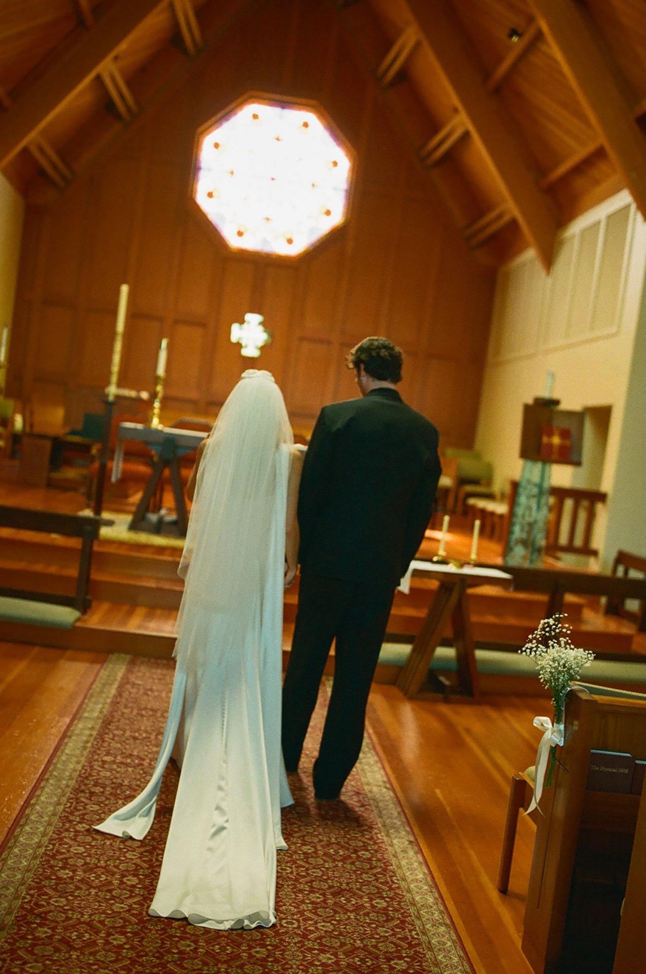 Tall wooden chapel interior with exposed beams and stained glass altar during a romantic Laguna Beach wedding ceremony.