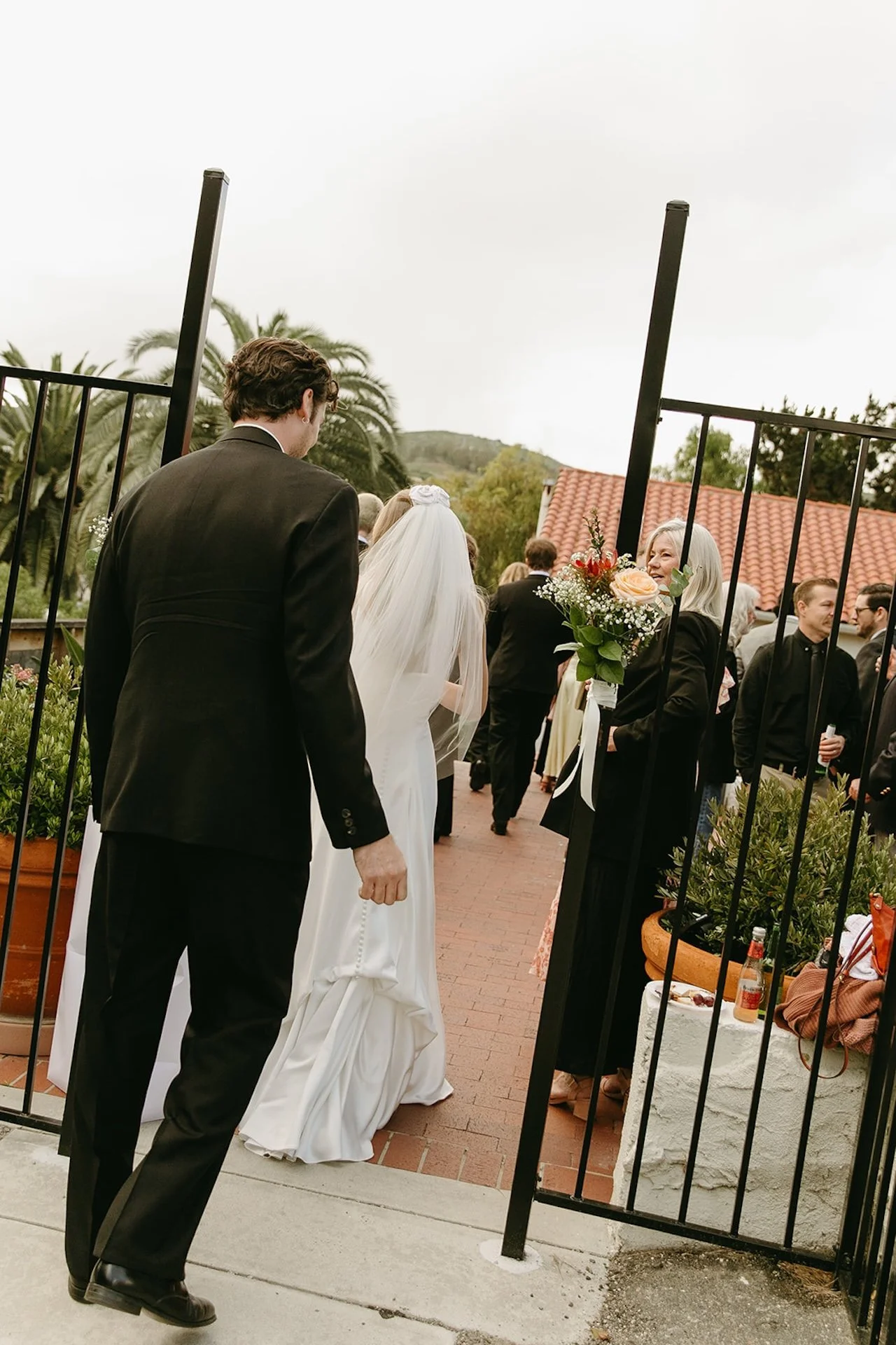Newly married couple walking through the gate toward guests after their Laguna Beach wedding ceremony.