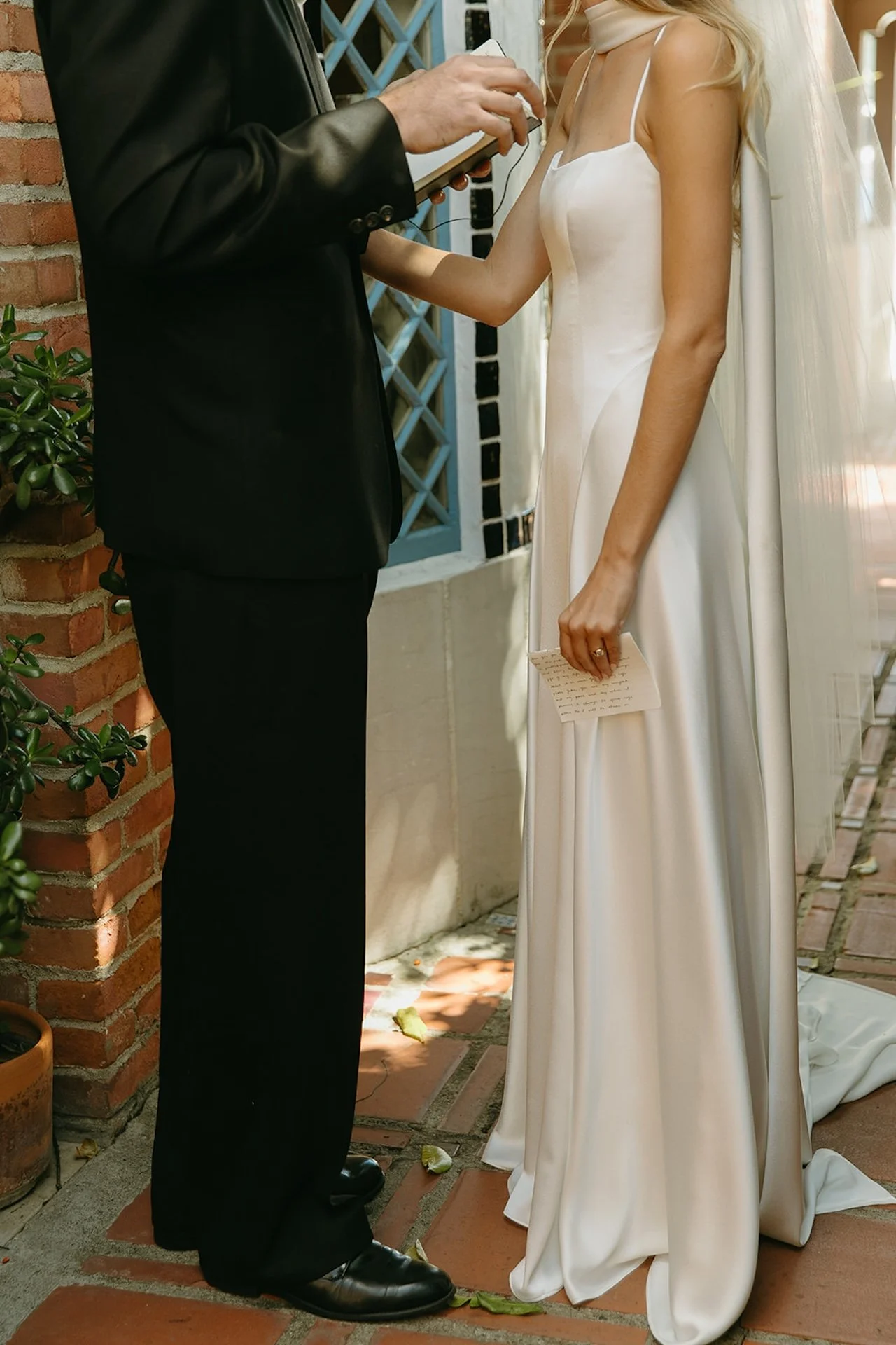 Bride holding and reading her handwritten vows during an intimate Laguna Beach wedding moment outside the church.