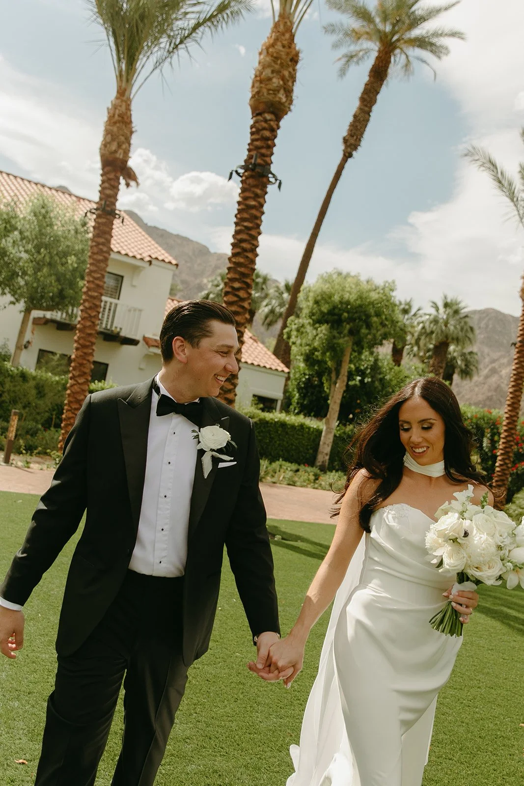 A bride and groom walking across a lawn at Palm Springs wedding venue PGA WEst