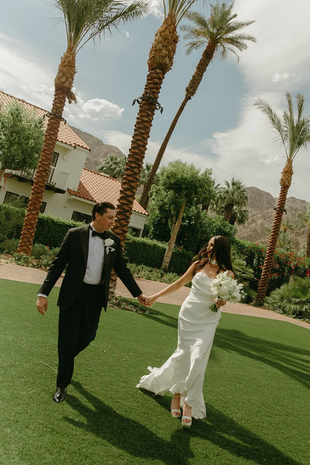 A bride and groom walking across a lawn at Palm Springs wedding venue PGA WEst