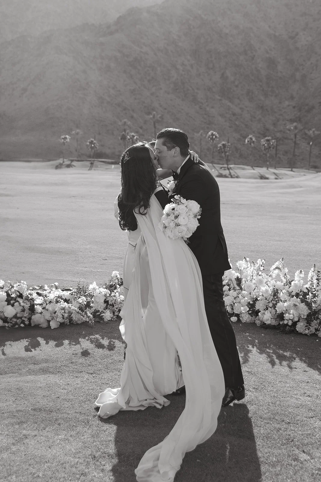 A black and white photo of a bride and groom kissing at their Palm Springs wedding venue