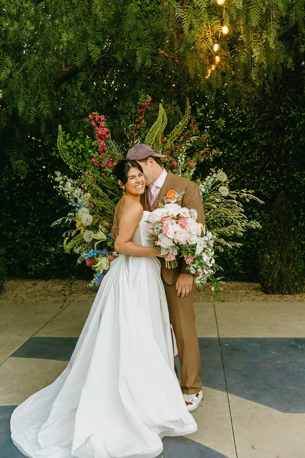 A bride and groom posing for photos at their unique wedding venue, the fig house