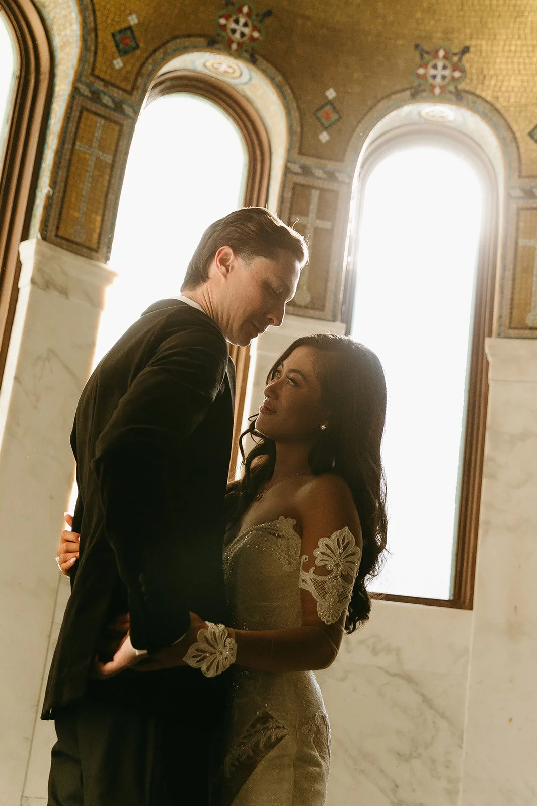 A bride and groom posing for photos inside of Vibiana