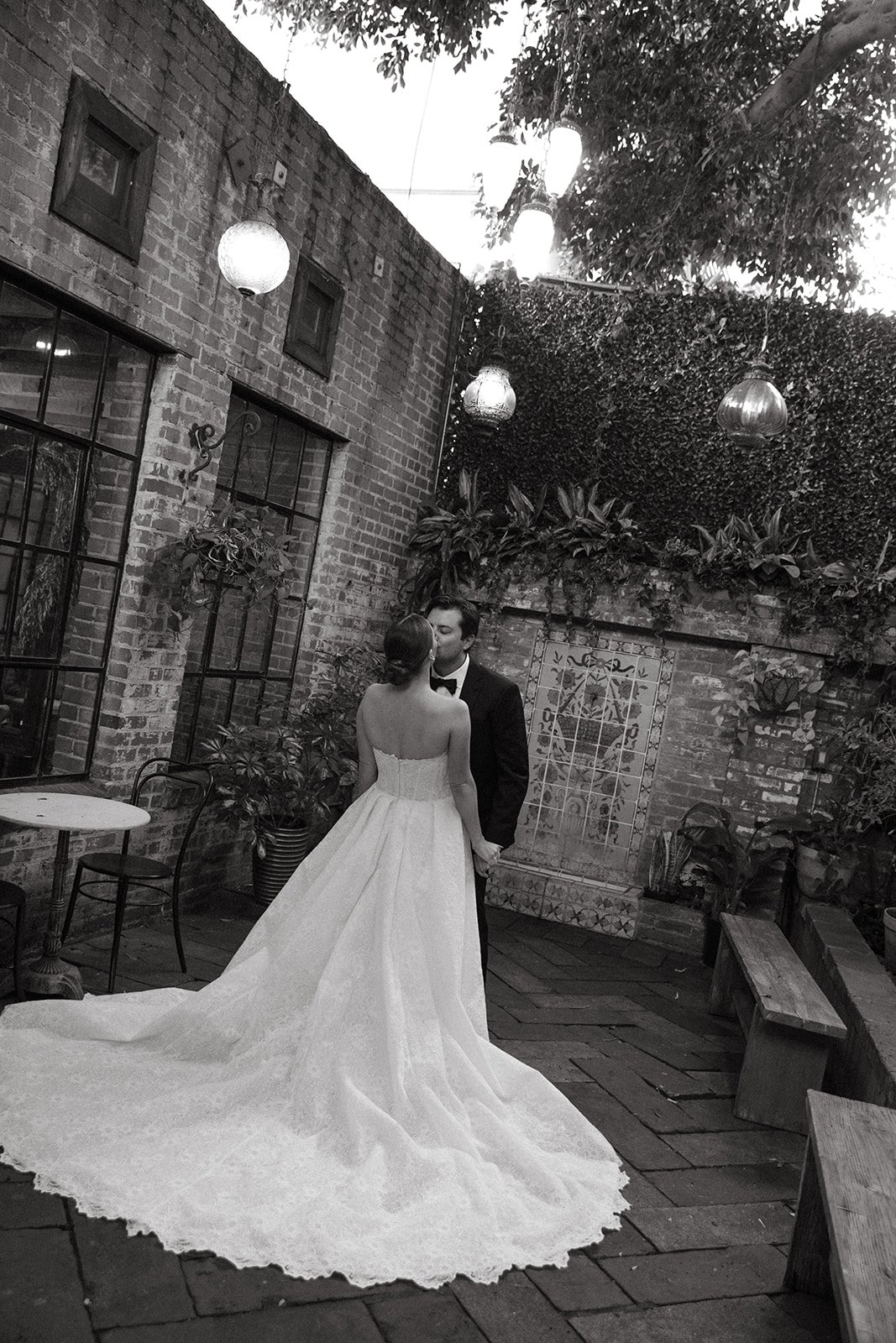 A black and white photo of a bride and groom walking through their unique wedding venue