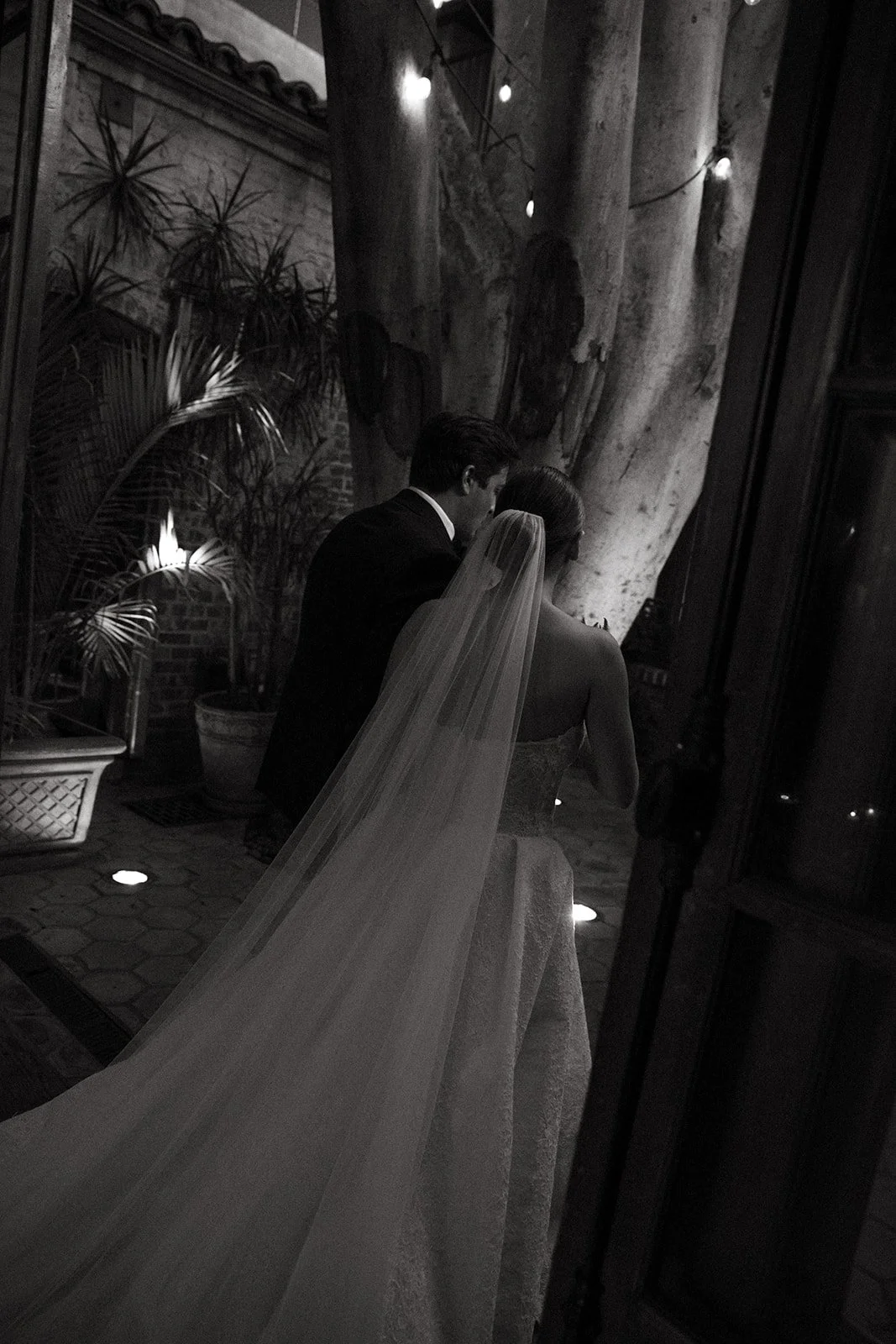 A black and white photo of a bride and groom walking through their unique wedding venue