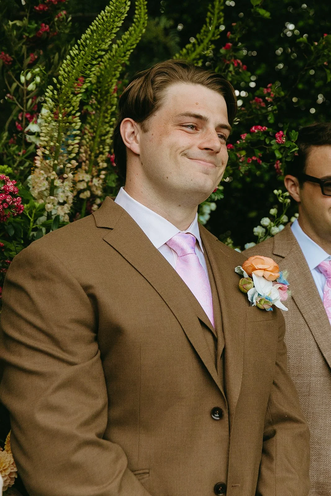 A groom watching a bride walk down the aisle with a tear in his eye