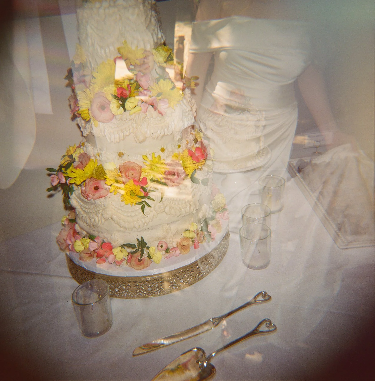 A film wedding photo of a bride and groom cutting a wedding cake