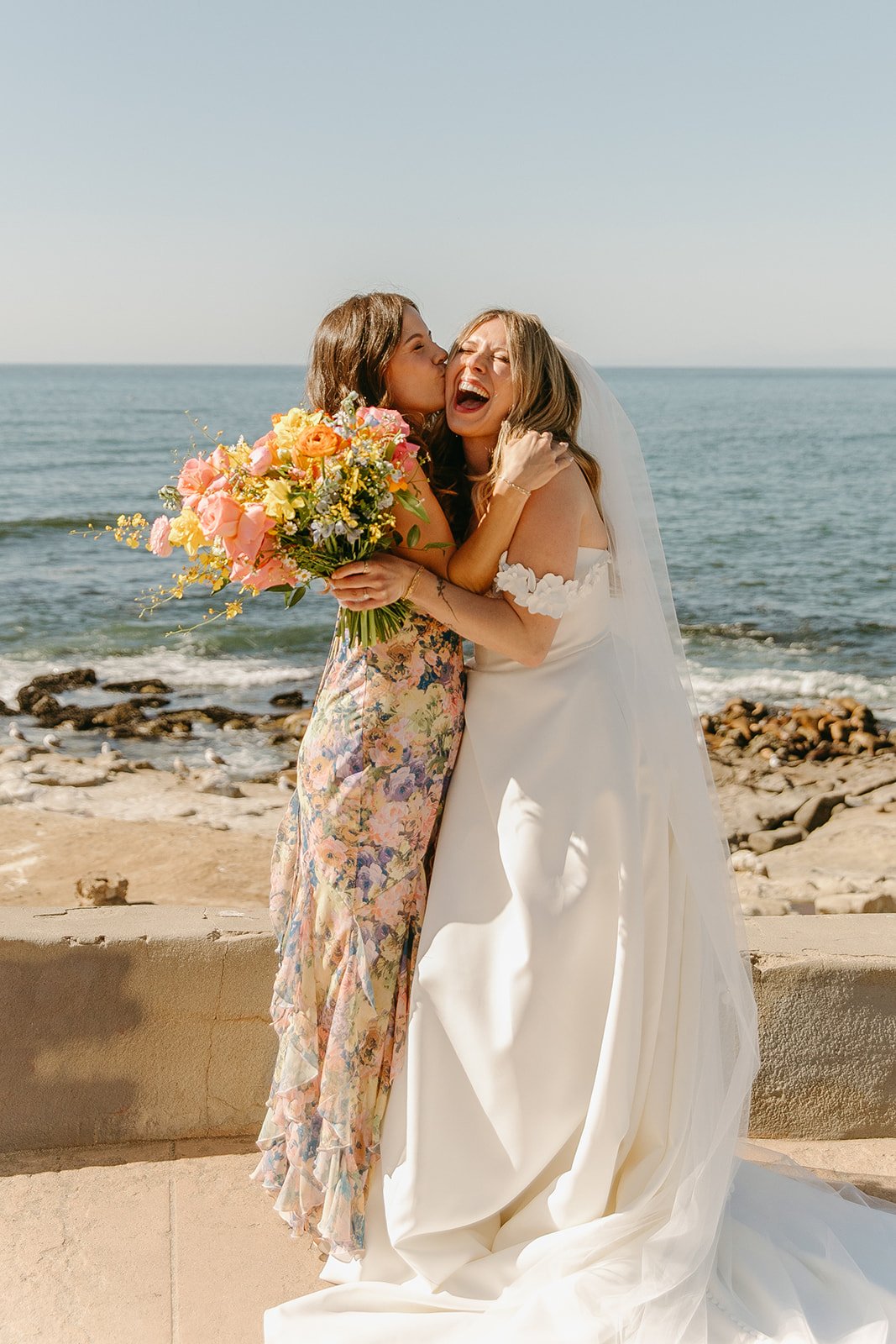 A bridesmaid kissing a bride on the cheek