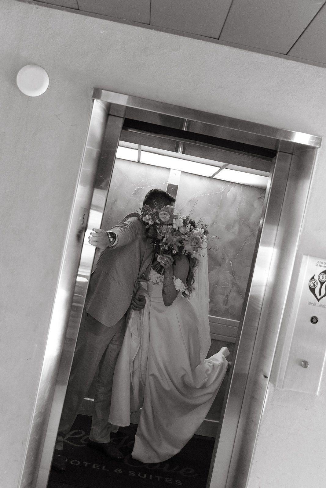 A bride and groom kissing in an elevator