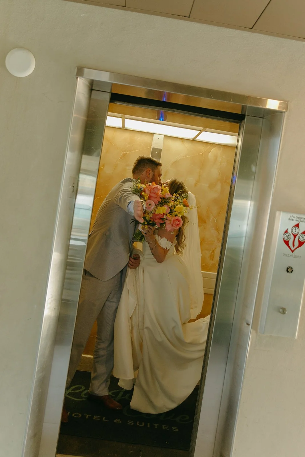 A bride and groom kissing in an elevator