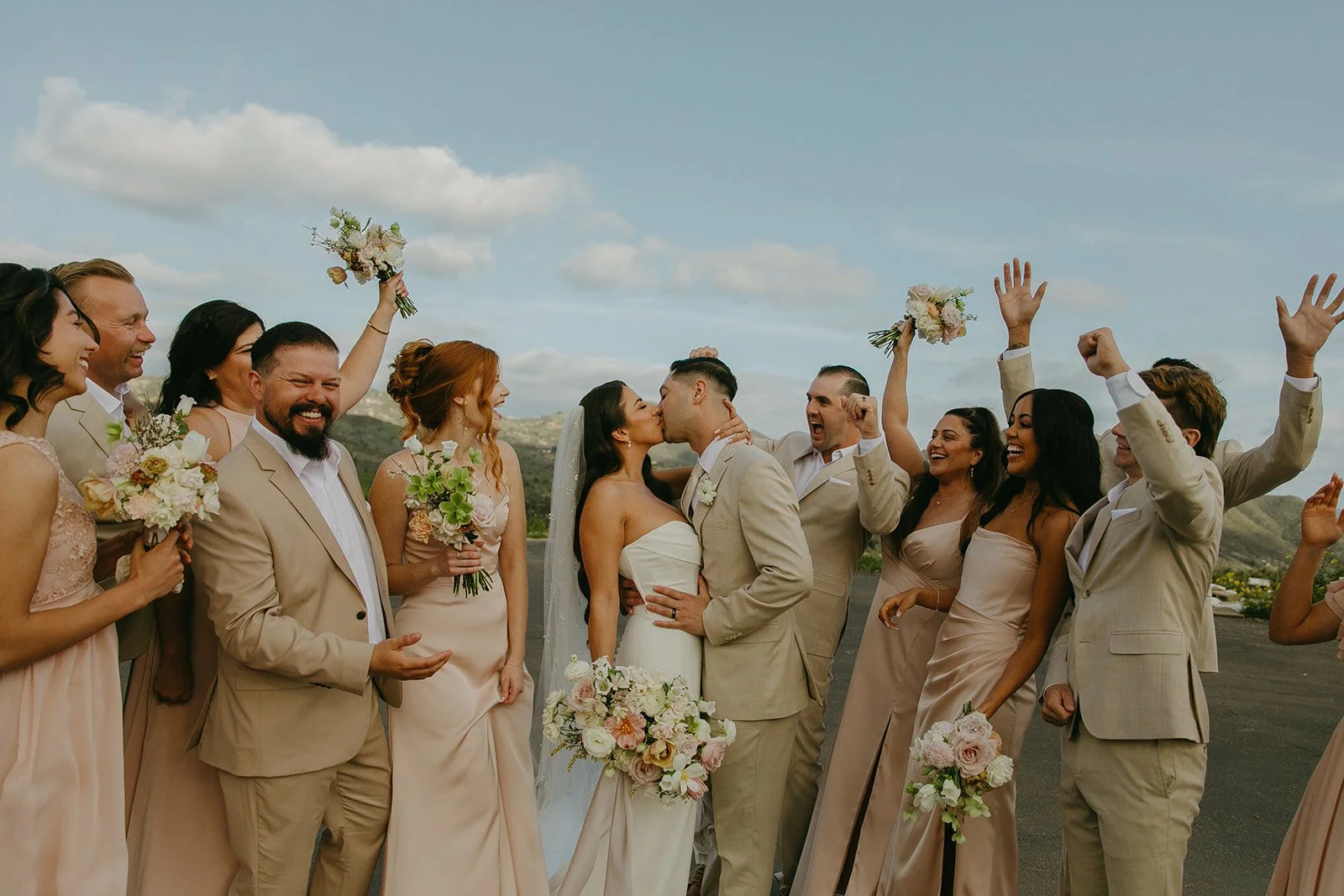 A wedding party photo with the bride and groom kissing