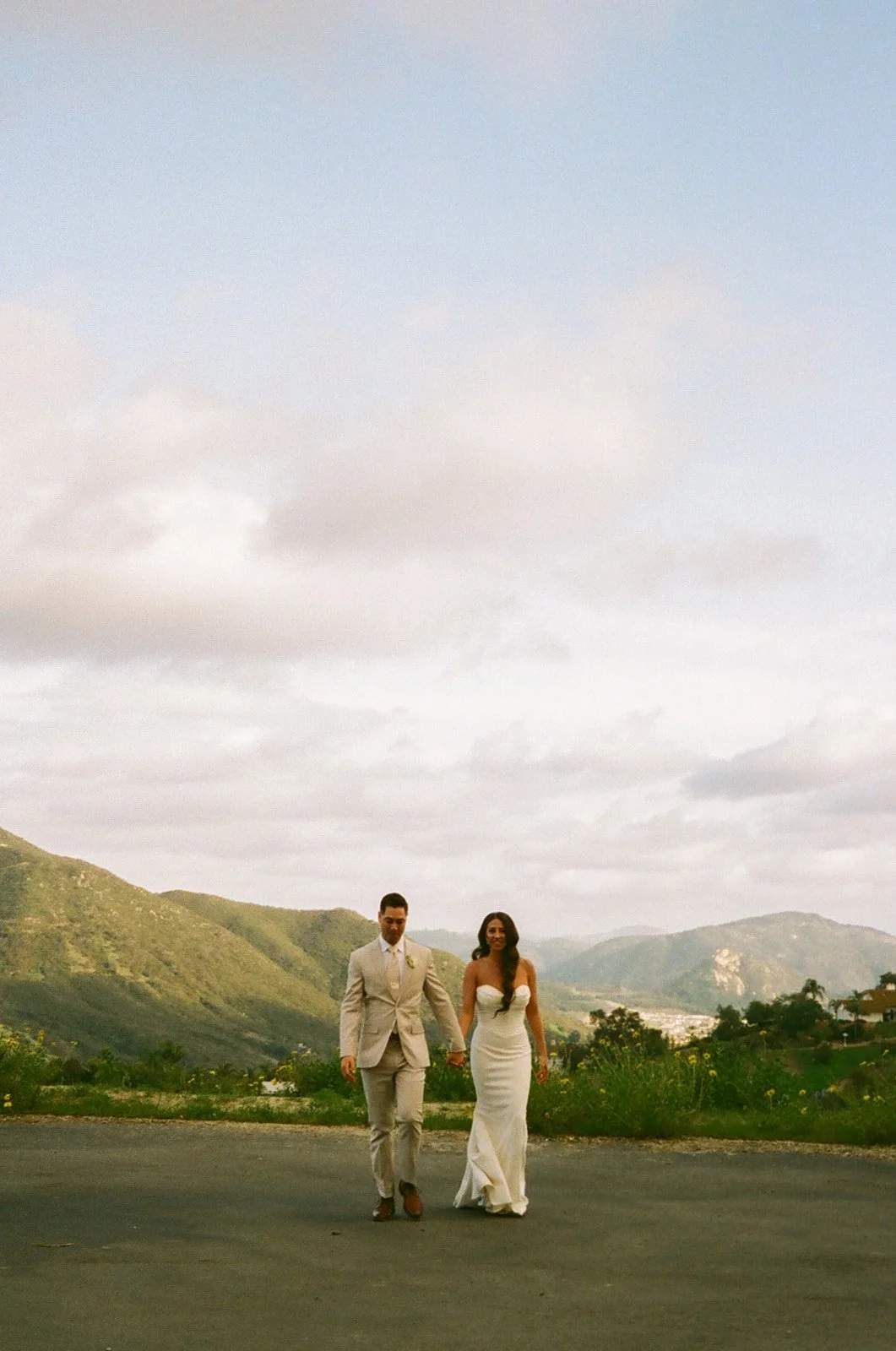 A bride and groom walking towards the camera at their mountain wedding venue